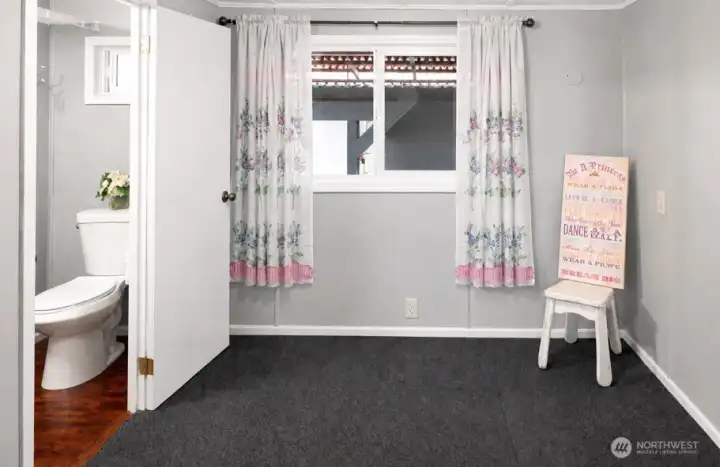 Second bedroom with half bathroom, window, and soft carpet flooring.