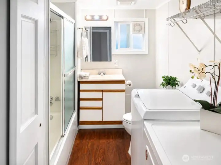 Bright full bathroom, vanity area, washer and dryer, and hardwood flooring.