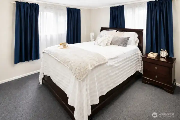 Primary bedroom with carpet, double windows, and natural light.