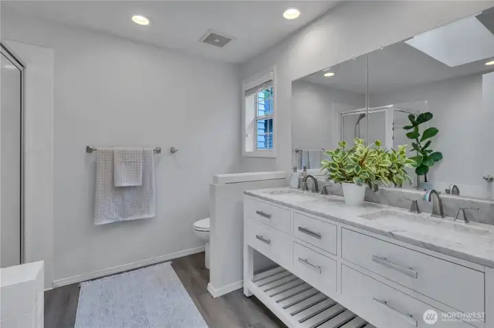 Primary bath with laminated tile flooring and skylight. Double vanity with storage.  Separate shower and garden tub.