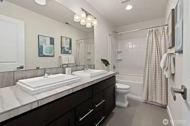 Full hall bathroom featuring a double-sink vanity, conveniently shared by the secondary bedrooms.