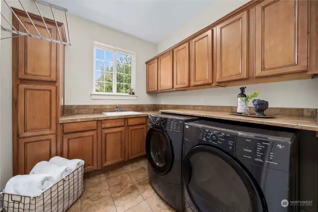 You'll love this dreamy laundry room full of storage cabinets and convenient utility tub.