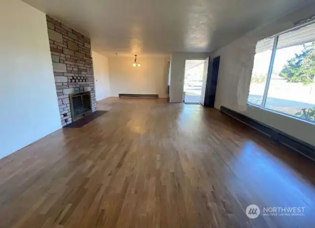 Livingroom room with hardwood floors and plaster walls. Floor to ceiling wood burning fireplace