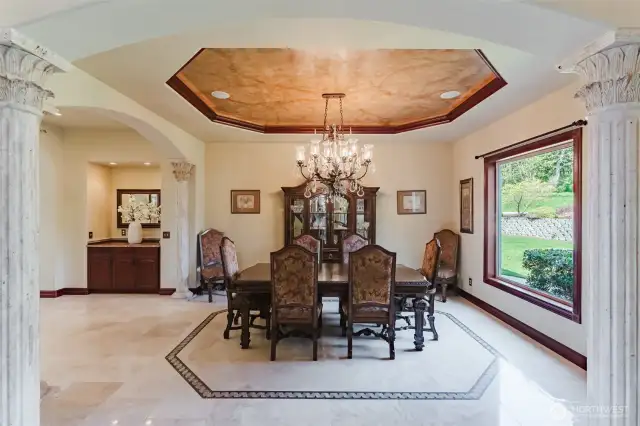 The formal dining area has recessed lighting with beautiful faux painted ceilings, an impressive crystal chandelier, and is surrounded by 8 solid marble columns with Temple of the Winds capitals throughout the lower living area. The butler pantry and bar are located near the formal dining, offering a perfect layout for entertaining.