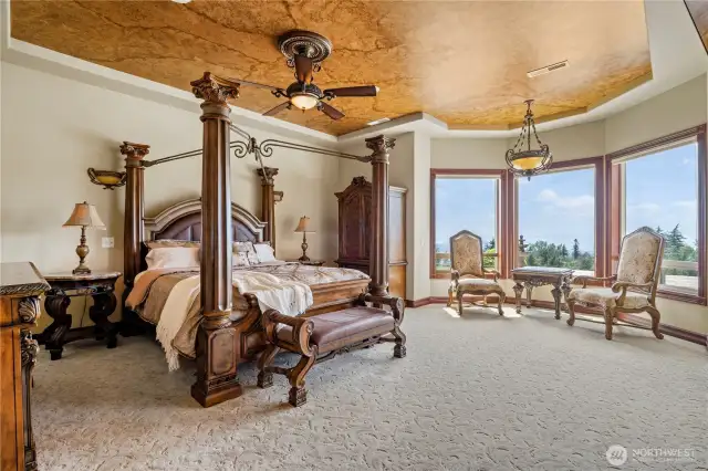 Primary Suite with recessed faux painted ceilings, sitting area overlooking the the pool, and patio door access to the pool and hot tub. There is a cozy fireplace with overhead recessed TV.