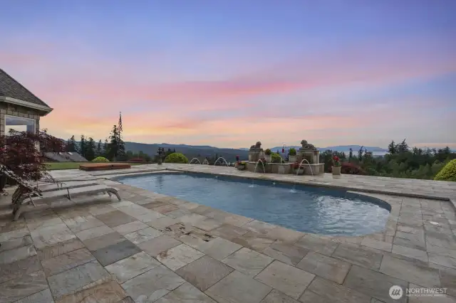 The pool at twilight with fountains. The pool deck is constructed with slate tile