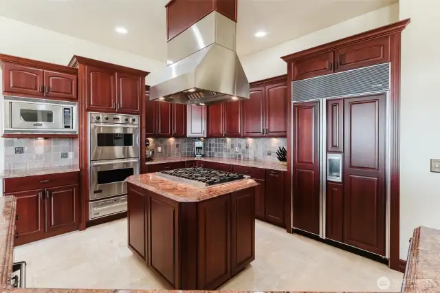 The custom dark cherry cabinets are soft-close, and have easy glide pull-out drawers. The chef's kitchen also includes Viking double ovens with additional pull-out warming drawer, and a Viking gas 6-cooktop stove