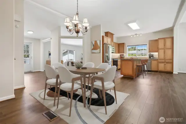 Formal dining room opens to kitchen and the family room, features vaulted ceilings and vinyl plank flooring.  Virtually staged photo.