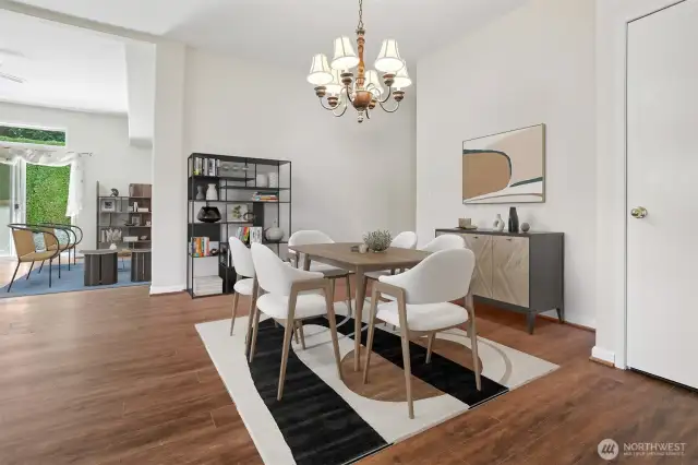 Formal dining room opens to kitchen and the family room, features vaulted ceilings and vinyl plank flooring.  Virtually staged photo.