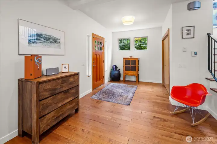The main entry foyer is located on the mid-level of the home, accessed from a warm wood front door. Hardwood floors and a small window provide a welcoming arrival space. Stairs to the upper level are visible to one side.