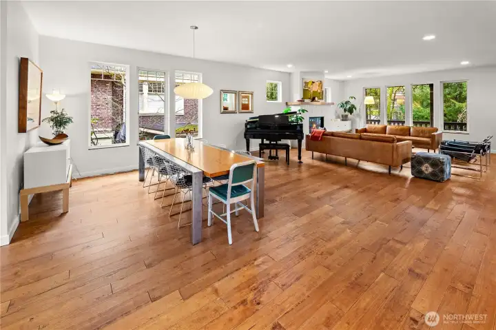 The scale of the main level comes into full view here, with hardwood floors stretching from the dining area through the piano alcove and into the living room beyond.