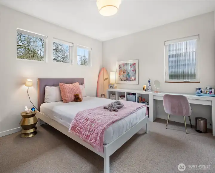 A bright and comfortable secondary bedroom with treetop views — equally suited for rest or study.