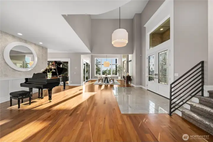 A dramatic two-story foyer with soaring ceilings, RH designer lighting, and a graceful curved staircase creates an unforgettable first impression