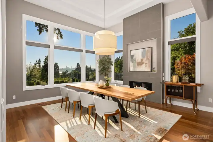 A dramatic dining room wrapped in floor-to-ceiling windows captures panoramic views of Lake Washington, the Seattle skyline, and breathtaking sunsets