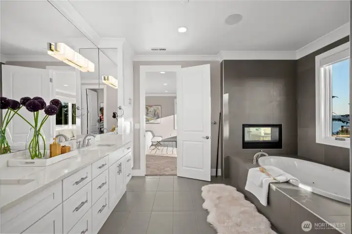 A spa-inspired primary bath offers a serene retreat with dual vanities, a soaking tub, a see-through fireplace, and tranquil Lake Washington views—bringing warmth, luxury, and relaxation to every day.