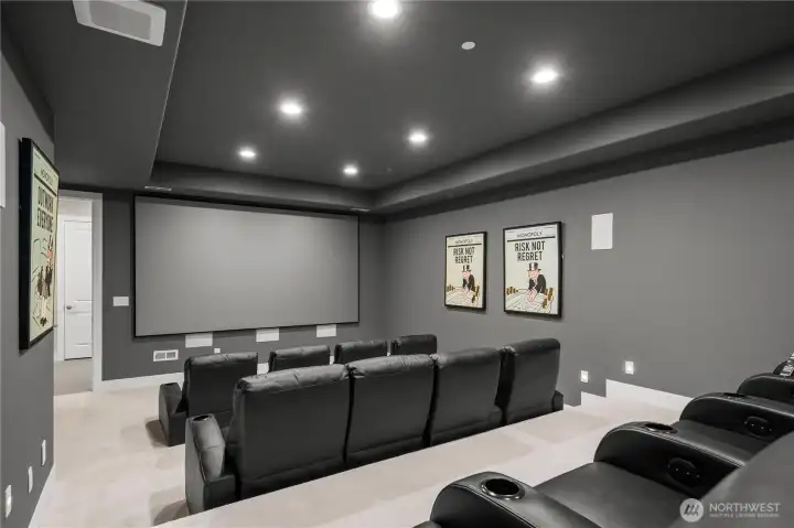Private home theater professionally designed for an immersive cinematic experience, featuring a 4K projector, 110-inch screen, luxury reclining theater seating, and integrated surround sound