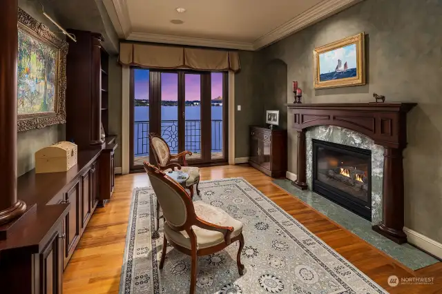 The Primary Suite begins with a private Sitting Room, offering a quiet space to read a book and relax next to the fire. Features include Gas Fireplace, Walnut Mantel, Marble Hearth, and Built-In Walnut Bookshelves.