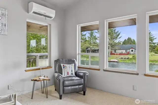 Living room corner offers a picturesque view of the stunning canal, complemented by a sleek Mitsubishi mini-split system for efficient heating and cooling.