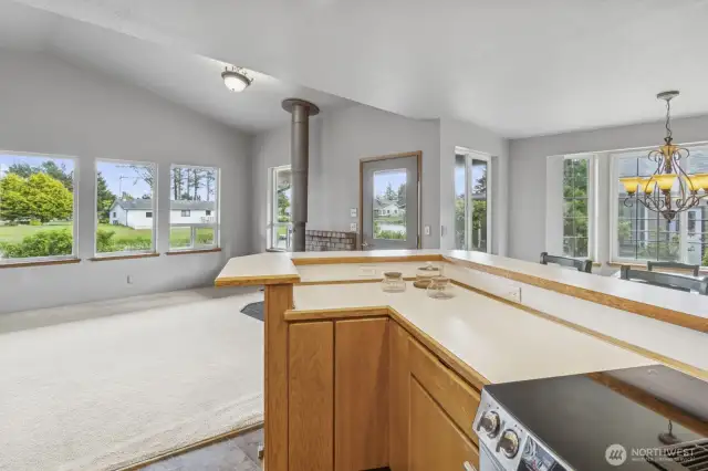 View from the kitchen toward the front door showcases the abundant natural light streaming through the large picture windows.