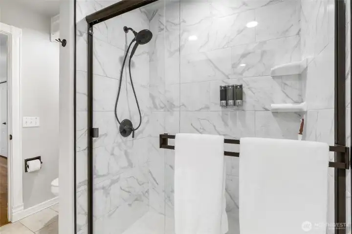 Gorgeous tiled shower with glass doors.