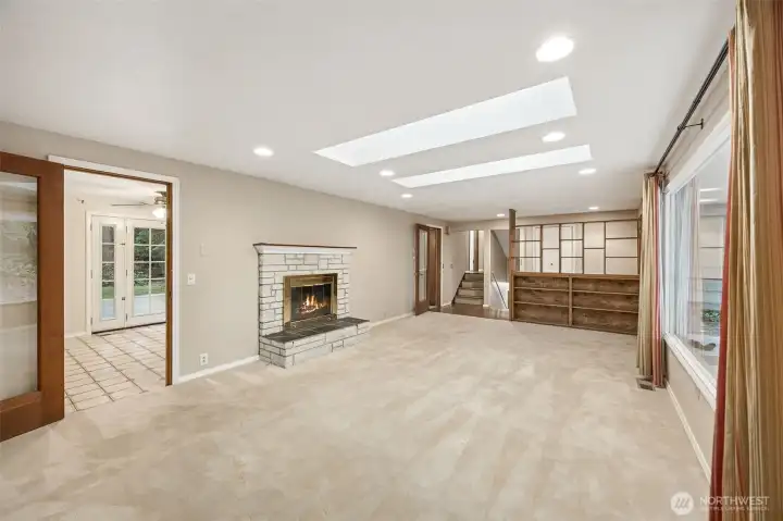 Bright and inviting living room filled with natural light. Skylights bring the outdoors in year-round. Cozy gas fireplace and built-in shelving create a warm gathering space.