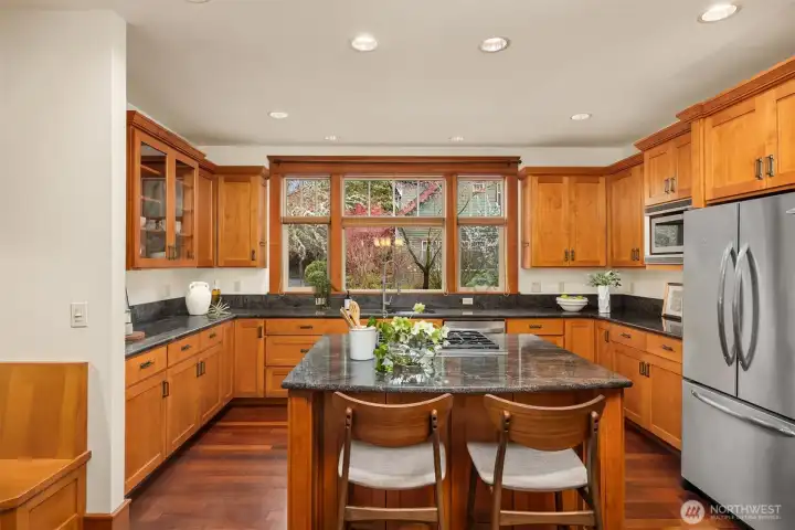 A wonderful kitchen designed for both everyday living and easy entertaining, featuring a downdraft island cooktop that keeps sightlines open, generous counter seating for casual meals or conversation, and a built-in dining nook that creates a warm, inviting space to gather.