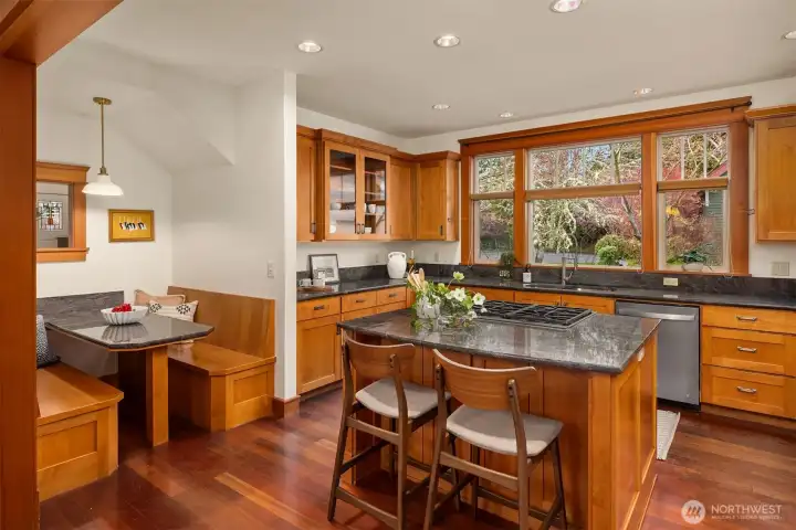 A wonderful kitchen designed for both everyday living and easy entertaining, featuring a downdraft island cooktop that keeps sightlines open, generous counter seating for casual meals or conversation, and a built-in dining nook that creates a warm, inviting space to gather.