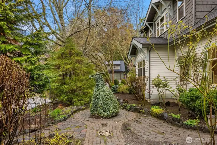 This is the side yard, thoughtfully designed as part of a cohesive outdoor setting. The entire property is beautifully landscaped with mature plantings and well-planned hardscape, creating texture, color, and visual interest throughout the seasons.