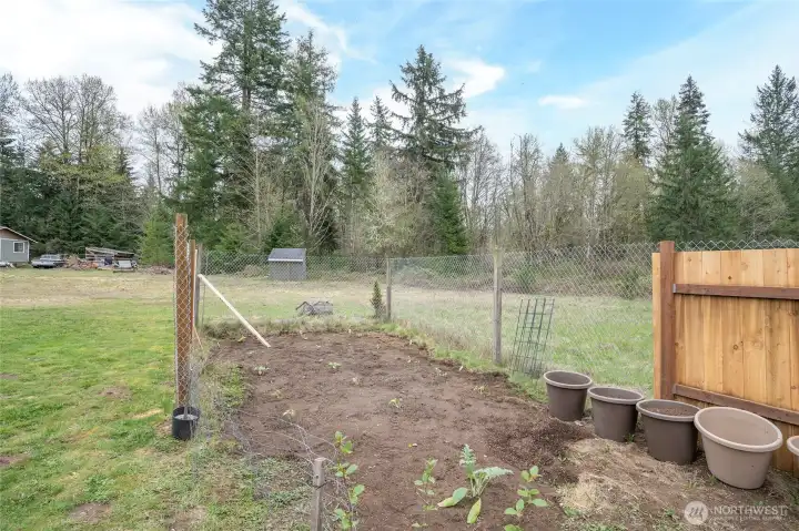 Garden space located just off the deck on the left side of the home, offering a peaceful spot for gardening and relaxation.