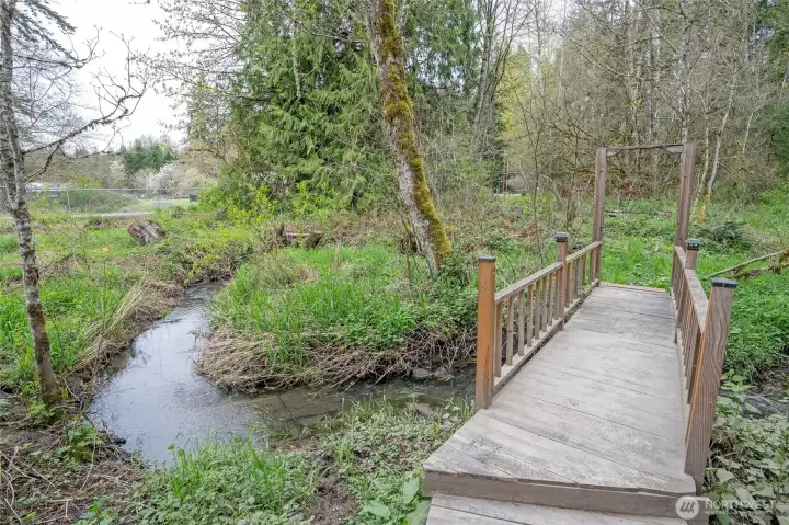 Cross the creek via the footbridge and explore the wooded portion of this serene 2.16-acre property.