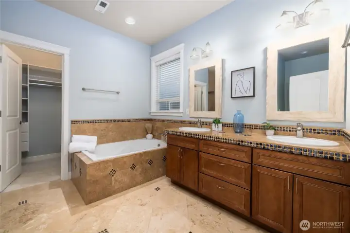 The private primary bath.  Custom in-lay in the tile floors and tub surround.  Deep soaking tub, plus stand-alone shower. Double vanity with lots of cabinet and drawer space. Walk-in closet.
