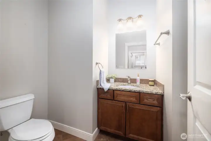 Main floor guest bathroom has a shower (not visible, behind door on right), granite counter, tile floor.