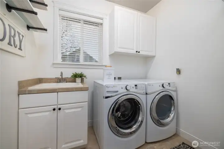 Good-sized laundry room offers a utility sink and storage.  Tile floors.