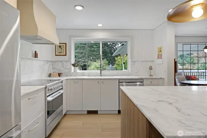 All-new appliances and cabinetry pair beautifully with marble surfaces, creating a clean, elevated look. The kitchen window frames a peaceful view of the backyard—perfect for keeping an eye on kids and pets at play while you cook and gather.