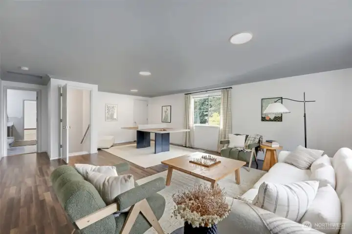 An expansive, light-filled living space offering an abundance of flexibility. To the right, an additional storage closet adds convenience, while a nearby door leads to the private staircase. To the left is the large bathroom, and then, two additional rooms—perfect for creating a fully functional separate living area.