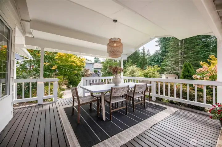 An absolutely expansive covered outdoor living space featuring three distinct areas, perfect for year-round enjoyment. This section highlights the inviting outdoor dining area—ideal for hosting and al fresco meals surrounded by lush, private landscaping.