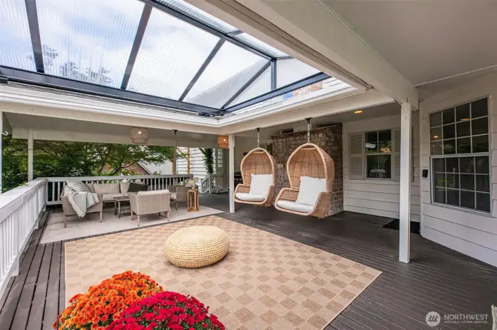 The second covered outdoor living space showcases a brand new, custom-designed roof system that floods the area with natural daylight while maintaining year-round protection. This serene setting offers a relaxing vantage point overlooking the lush backyard, complemented by the soothing ambiance of nearby water features—an ideal retreat for quiet mornings or elevated outdoor lounging