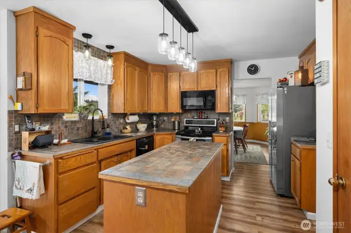 Warm and functional kitchen featuring abundant oak cabinetry, a center island, updated pendant lighting, and generous workspace for cooking and gathering. Warm and functional kitchen featuring abundant oak cabinetry, a center island, updated pendant lighting, and generous workspace for cooking and gathering.