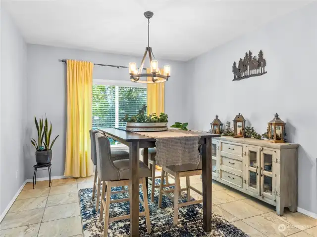 There is room to entertain a crowd in this spacious dining room. Handsome lighting, a large windo and tall ceilings make it feel spacious and bright