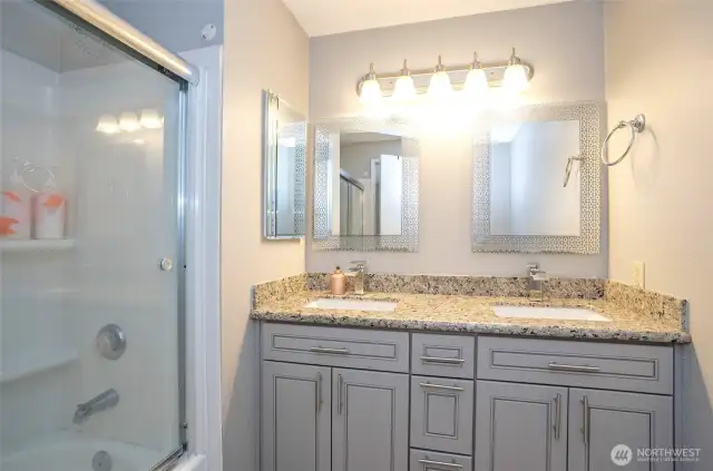 The primary bath offers dual sinks set in sleek granite countertops, providing both convenience and a touch of luxury.