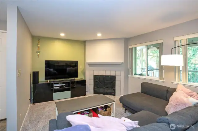 Another angle of the living area showcases the cozy wood-burning fireplace, with large picture windows offering a glimpse of the private deck beyond.