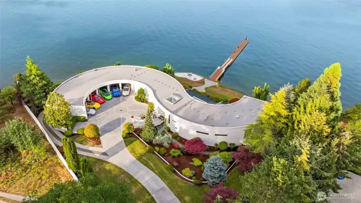 From above, the S House reveals its sculptural form — a sweeping arc that cradles a 6-bay showcase garage and embraces Wollochet Bay. Impeccably landscaped grounds flow to a private deepwater dock, ready to welcome a 60-foot yacht