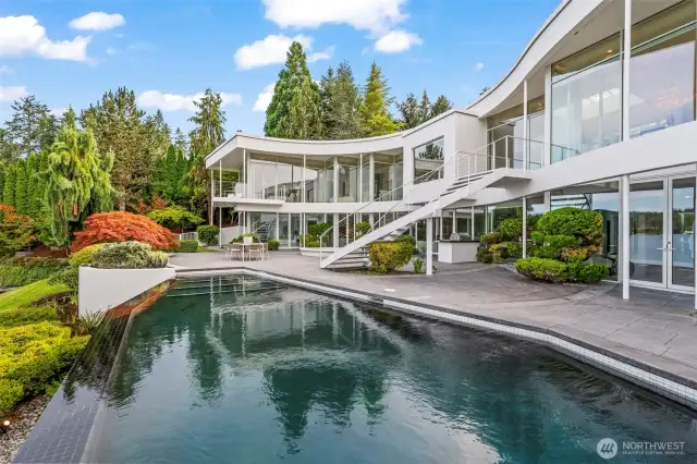 Infinity-edge elegance — the pool seems to pour into Wollochet Bay, mirroring the home’s fluid curves and walls of glass. Here, every swim is framed by architectural brilliance and lush Pacific Northwest beauty."