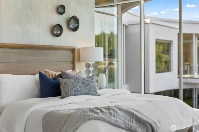 serene tones create a peaceful retreat in the primary suite, framed by architectural windows that capture the home’s modern elegance.