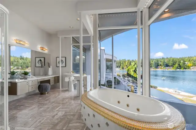 One of a kind primary bath pairs panoramic views with luxurious gold and marble finishes including a jetted soaking tub framed in gold tile.