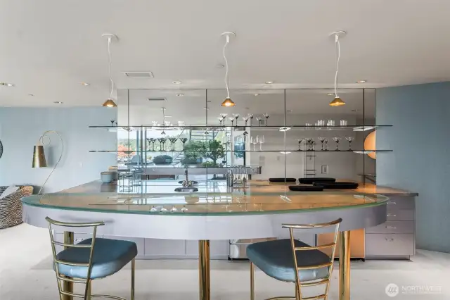 The mirrored back bar with lucite cabinetry reflects the waterfront views, making it the perfect spot to mix cocktails while guests mingle between the game tables and the patio.