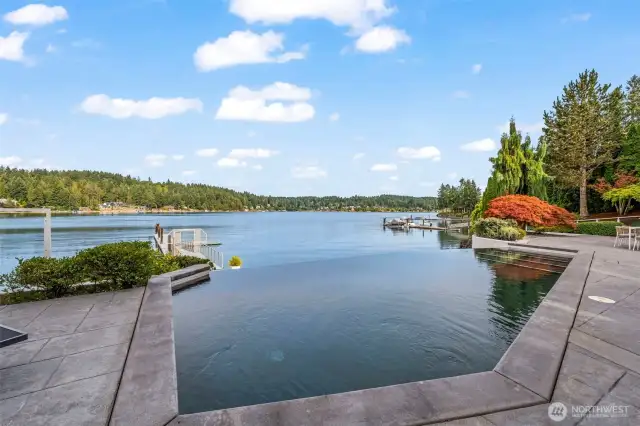 An infinity-edge pool appears to merge with the bay, drawing your eye toward your private dock and endless days on the water