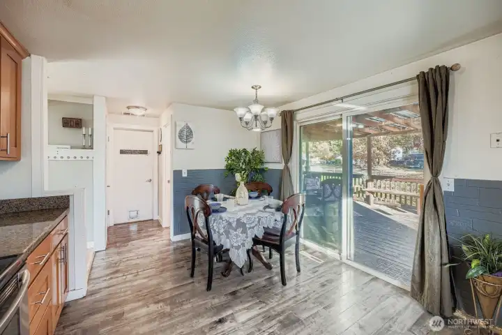 Dining area in kitchen with faux brick paneling, sliding door to covered deck & back yard which overlooks greenbelt