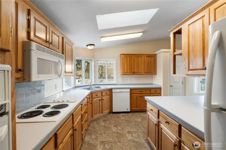 Large, open kitchen with extensive storage, generous prep space, and a sunny corner window that brightens the entire room.