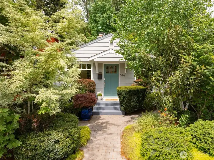 House is surrounded by landscaped gardens with established plants and trees.